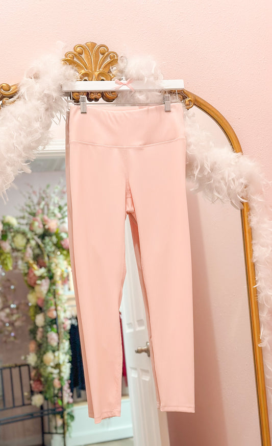 Pink pants on a hanger against a decorative background with flowers and feathers.